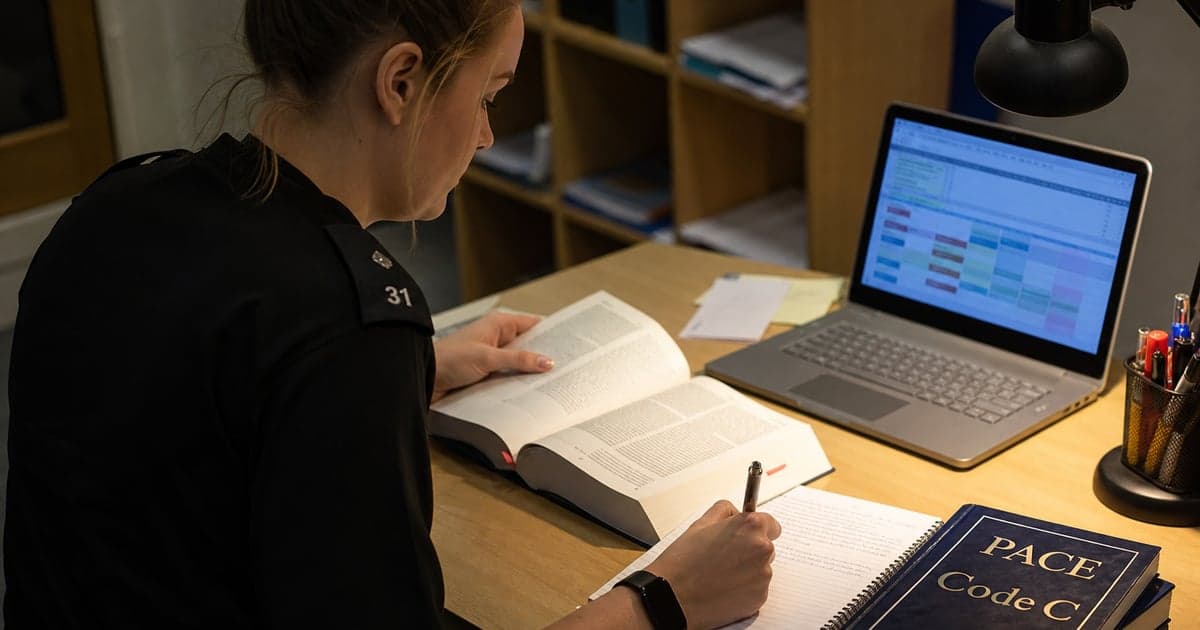 Police station representative studying PSRAS revision plan at a desk